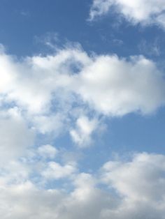 the airplane is flying high in the sky with white clouds behind it and blue skies above