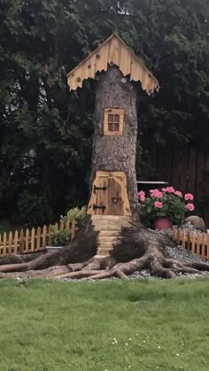 a tree house built into the side of a tree in a yard next to a fence