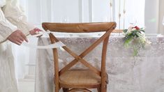 a person standing next to a table with a chair on it and a ribbon tied around the chair