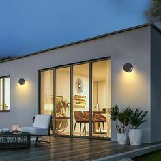 a modern house with glass doors and patio furniture