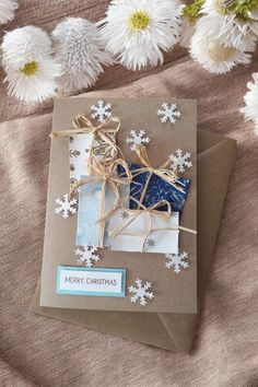 a christmas card with snowflakes on it and a brown envelope that has an ornament in the shape of a horse