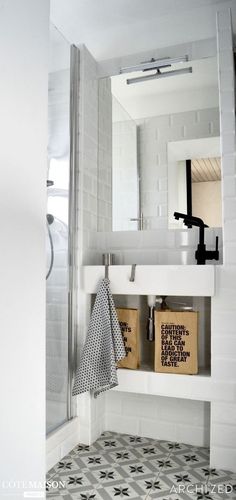 a bathroom with a sink, mirror and tiled flooring in white color scheme on the walls