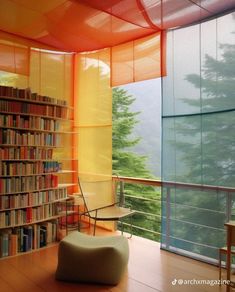 a room with a chair, bookshelf and window that looks out onto the mountains