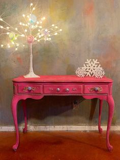 a pink table with a snowflake tree on top and lights in the middle