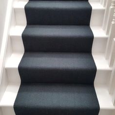 black carpeted stairs with white handrails leading up