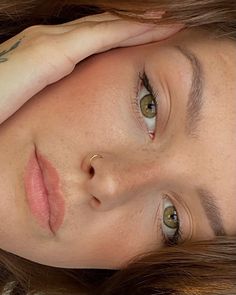 a close up of a person laying down with her hand on her head and eyes closed