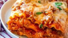 a white plate topped with lasagna covered in sauce and cheese