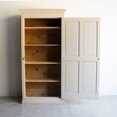 an empty bookcase next to a white wall with doors on both sides and drawers in the middle