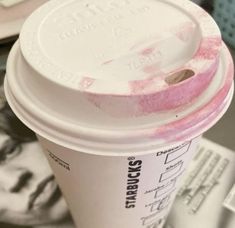 a close up of a coffee cup with pink stuff on the lid and paper napkins around it