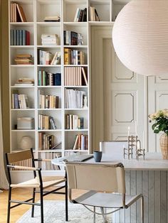 a dining room table and chairs with bookshelves in the background