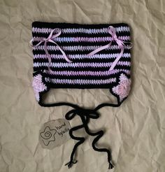 a crocheted purse with pink and black stripes on the front, tied to a string