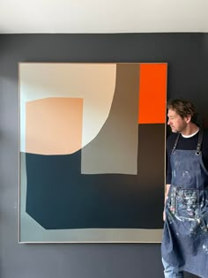 a man standing in front of a painting on the wall with an apron over his shoulder