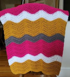 a crocheted blanket sitting on top of a wooden chair