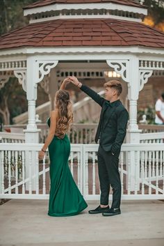 a man and woman dancing in front of a gazebo