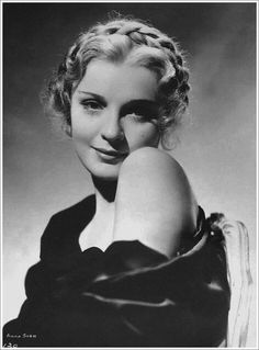 an old black and white photo of a woman with her arm over her shoulder, looking at the camera