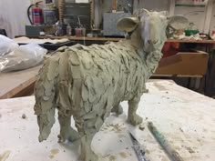 a clay sculpture of a sheep on a workbench