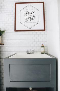 a bathroom with a sink, mirror and framed sign above it that says sup to go