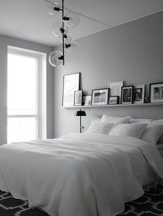 a white bed sitting in a bedroom next to a window with pictures on the wall