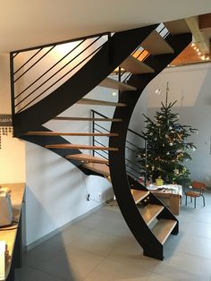 there is a spiral staircase in the living room with a christmas tree on the table