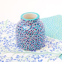 a blue vase sitting on top of a table next to a piece of paper with polka dots