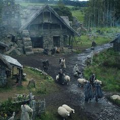 a group of people with sheep in front of a house