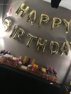 a birthday party with gold foil balloons and confetti on the table in front of it