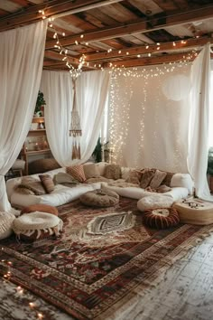 a living room filled with lots of white furniture and lights hanging from the ceiling above