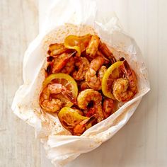 a bowl filled with shrimp and peppers on top of a white table next to a fork