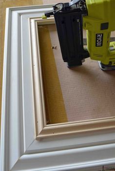 an electric nailer is being used to attach the trim on a framed photo frame