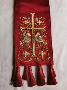 an embroidered cross with tassels on a white sheet