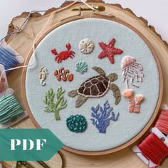 an embroidery project with sea animals and seashells on it, next to thread spools