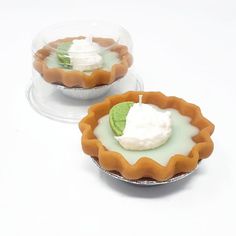 two small pies sitting on top of each other with whipped cream and green leaves