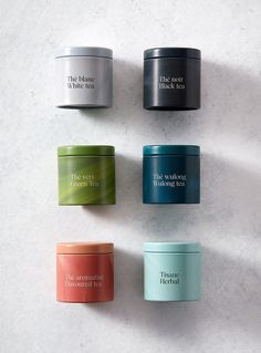 four different colored containers sitting next to each other on a white counter top, with the lids open