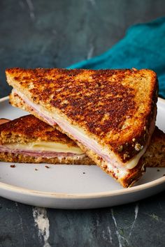 a grilled ham and cheese sandwich on a white plate with a blue napkin in the background