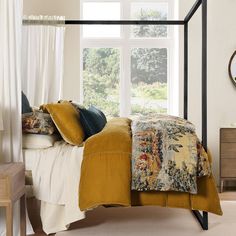 a bedroom with a four poster bed and white curtains on the window sill above it