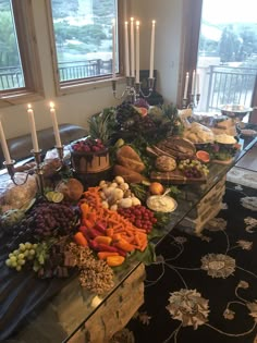 a table filled with lots of different types of food and candles on top of it