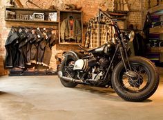 a motorcycle parked in a garage next to some shelves filled with jackets and coats on hangers