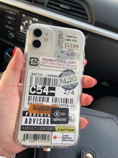 a person holding up a cell phone case that has some stickers on the back of it