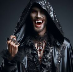 a man dressed as dracula holding a ring in his right hand and smiling at the camera