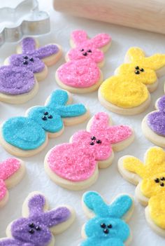 decorated cookies with different colored frosting on a white tablecloth next to cookie cutters