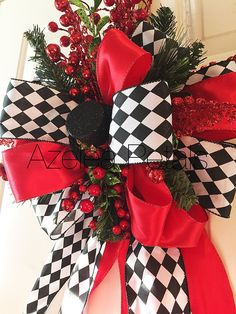 a red and black christmas wreath with holly, berries and ribbon on the front door