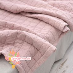 a bed with a pink quilted cover and pillow on it's back side