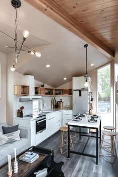 an open kitchen and living room area in a house with wood floors, white walls and ceilings