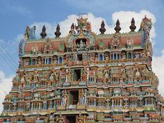 an elaborately decorated building with statues on the front and sides, against a cloudy blue sky