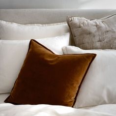 a bed with white and brown pillows on top of it