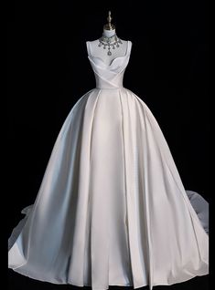 a white wedding dress on display in front of a black background with the back of it's neckline