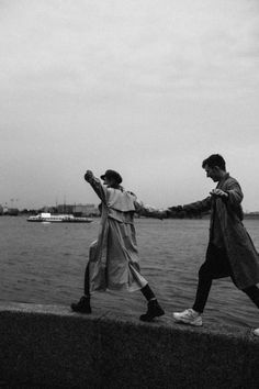 two people walking along the edge of a body of water