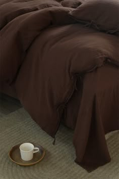 a bed with brown linens and a coffee cup on the floor next to it