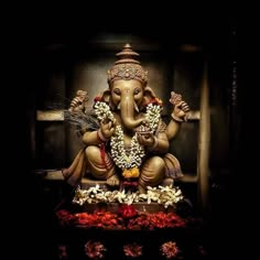 an elephant statue sitting on top of a wooden table filled with flowers and greenery