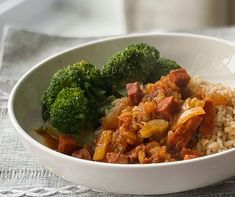 a white bowl filled with rice and meat next to broccoli on a table